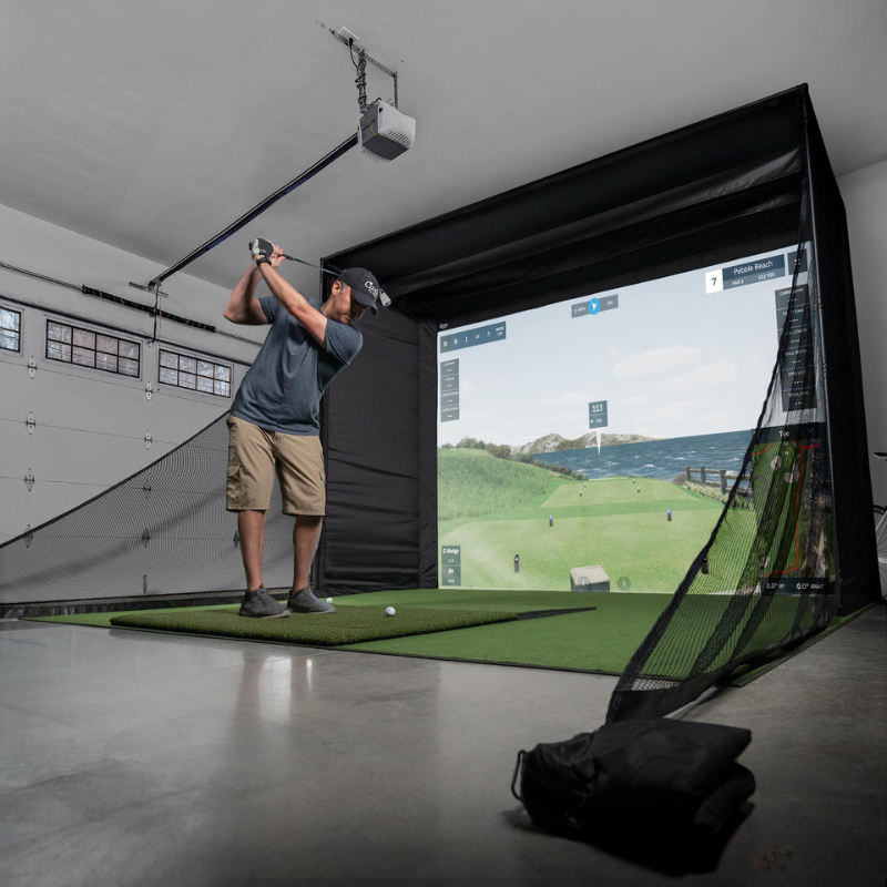 Carl&#39;s Place DIY Golf Simulator Enclosure Kit with Impact Screen and golfer hitting balls on a launch monitor.