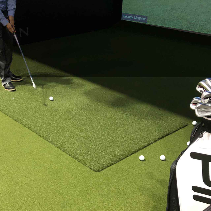 EZTee Hybrid Hitting Strip in golf simulator bay with golf club and ball.