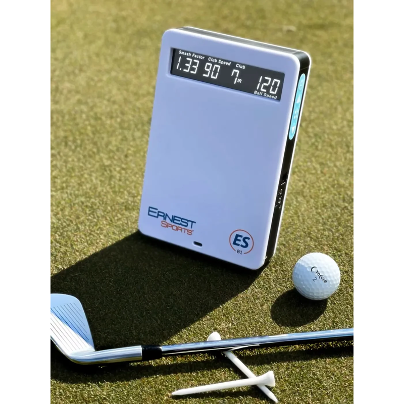 Ernest Sports ESB1 launch monitor on the grass beside a golf ball and iron.