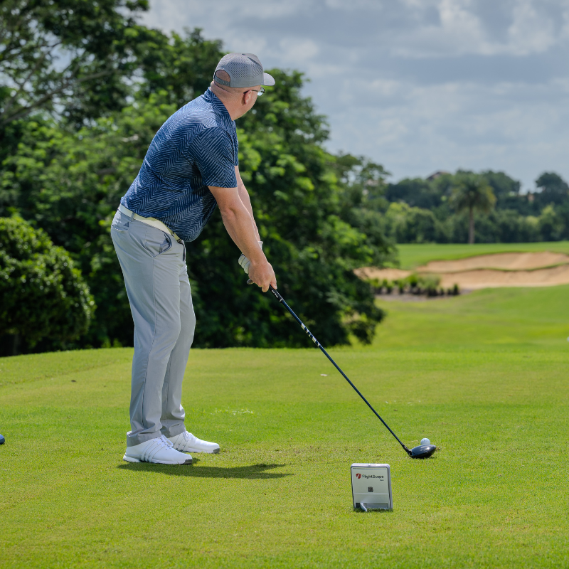 FlightScope Mevo Gen2 Launch Monitor man teeing up outside.