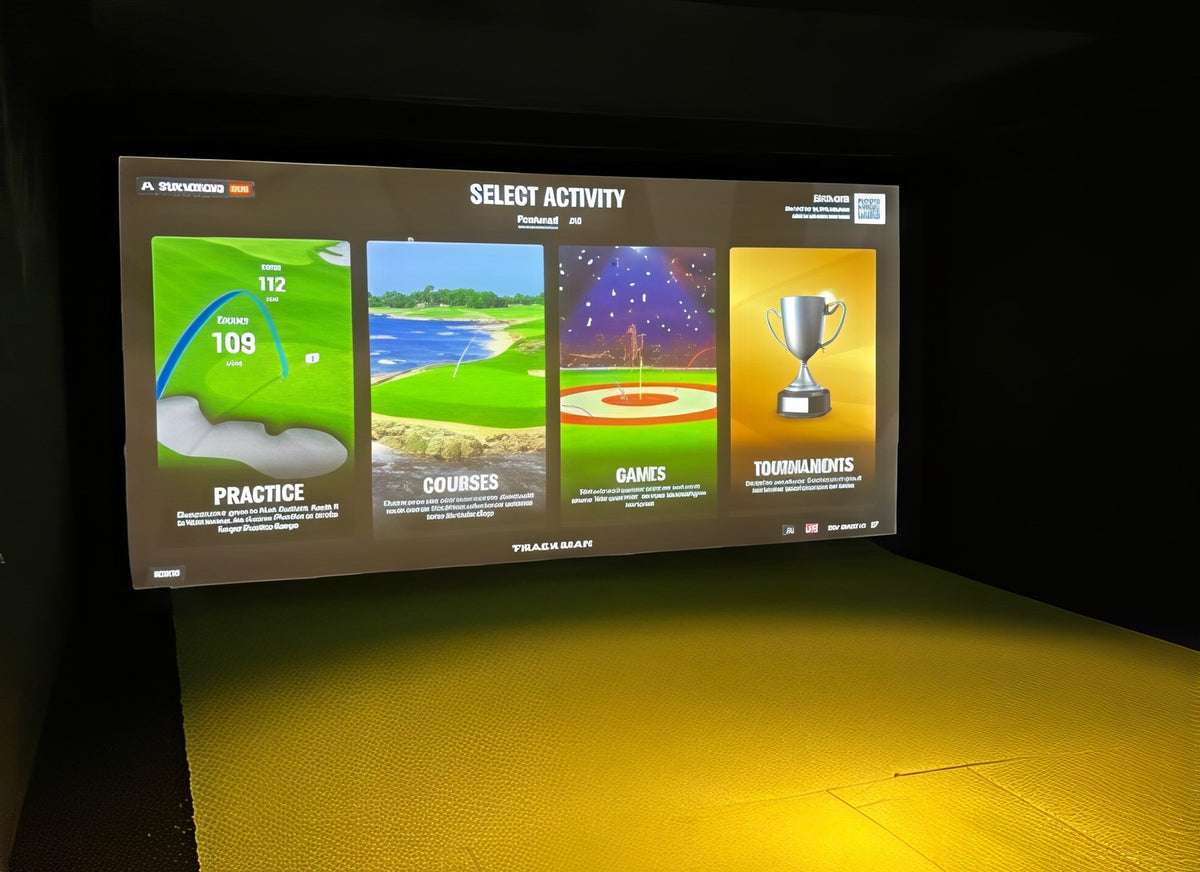 Finished golf simulator bay with dark walls and Trackman software on the screen
