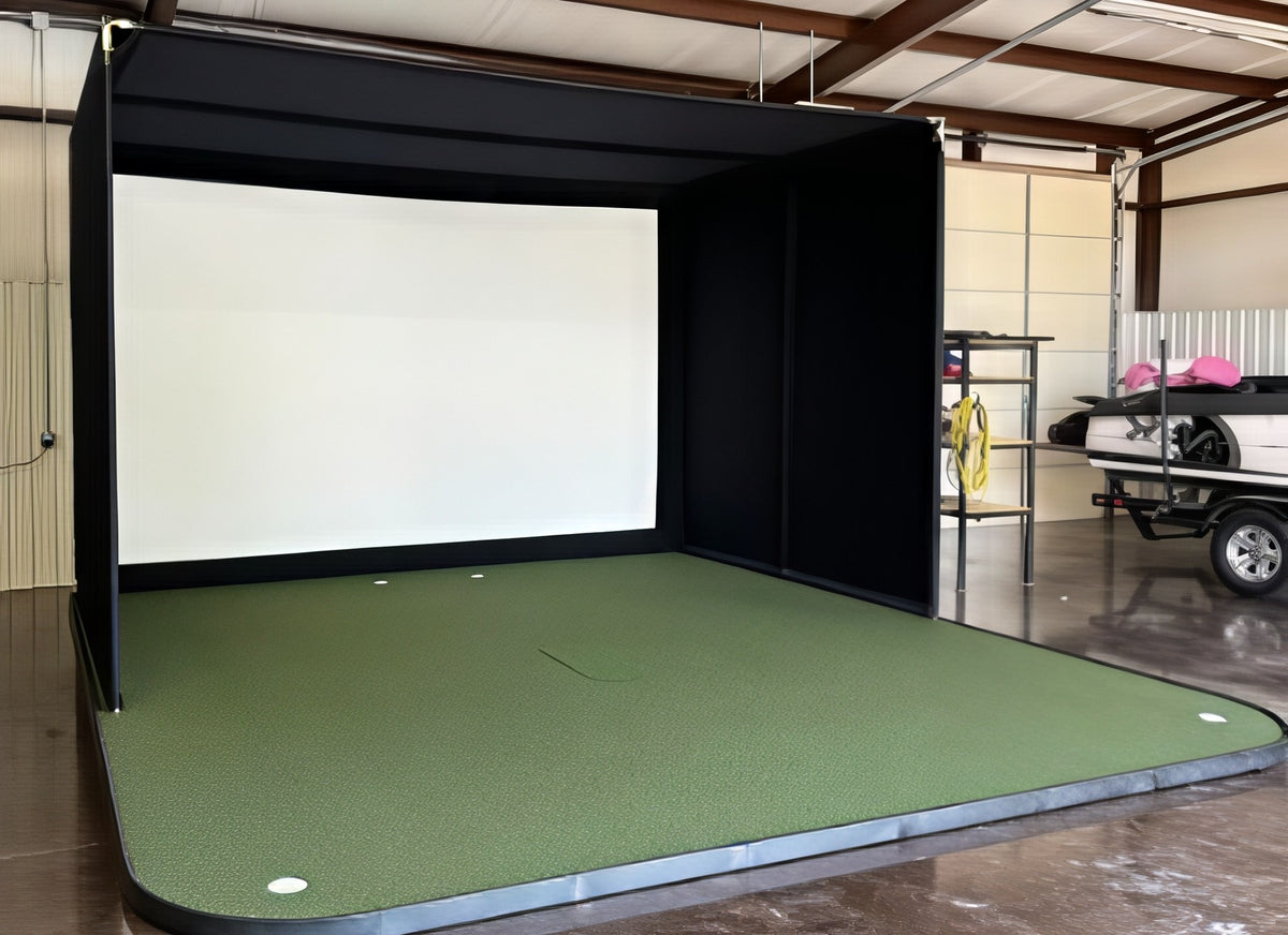 Finished golf simulator installation in a garage with an enclosure on a raised turf platform