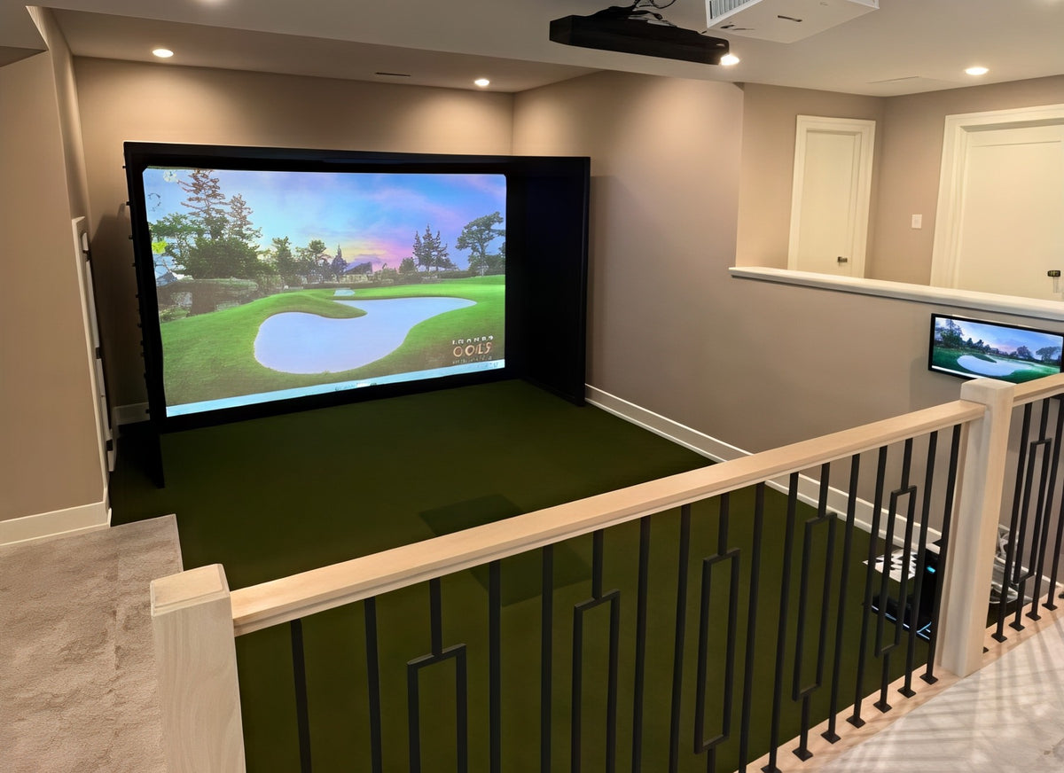 Finished golf simulator bay in an open room, seen from the stair railing