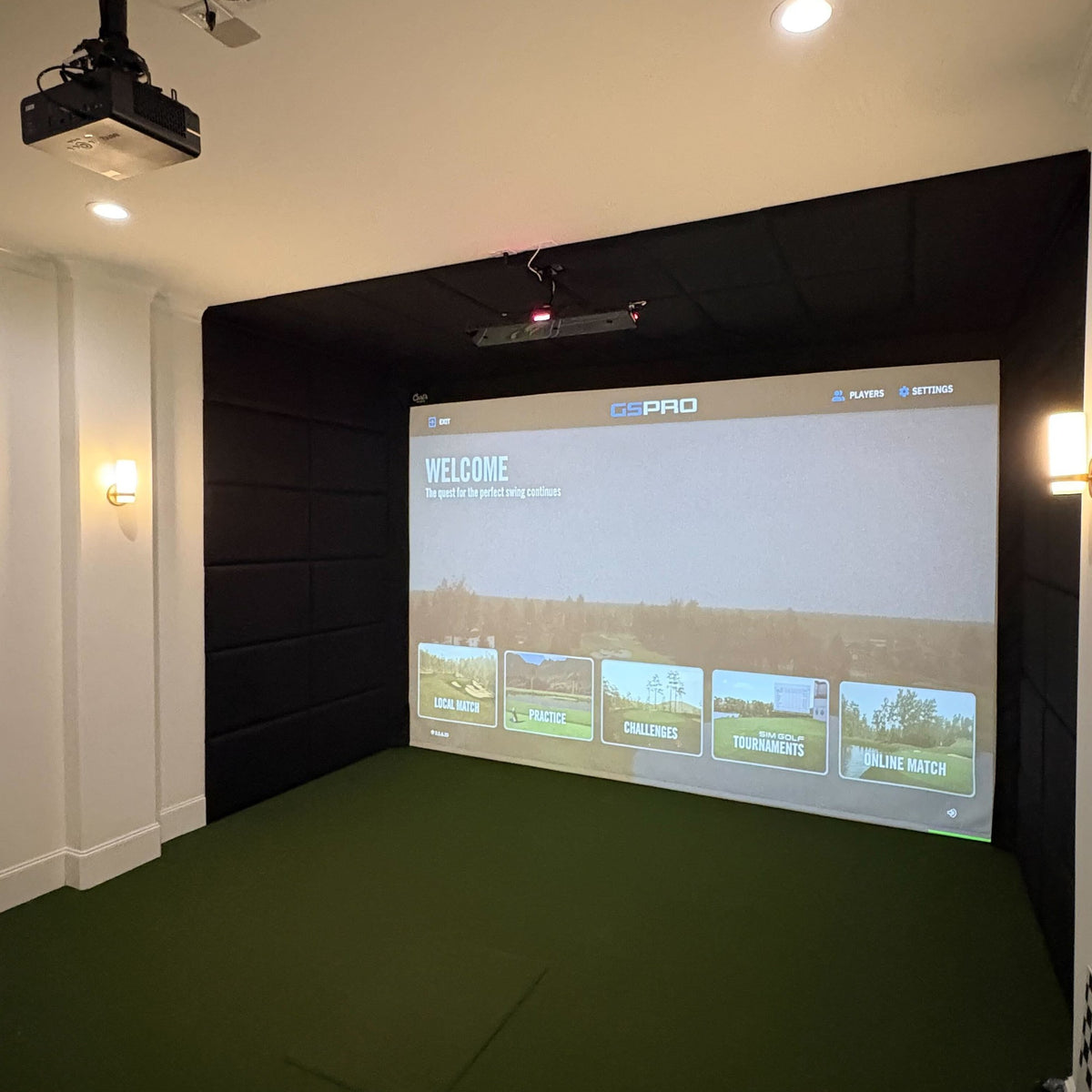 Finished IGO golf simulator installation: a padded bay with a ceiling-mounted projector and GSPro on the impact screen