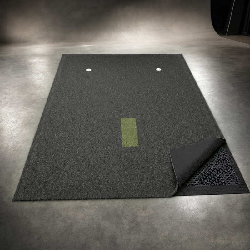 IGO Single-Level Golf Simulator Flooring with one corner of the black turf folded back to show the interlocking floor tiles underneath.