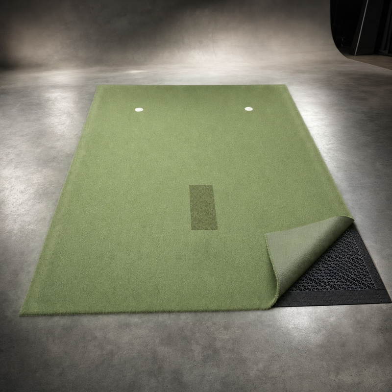IGO Single-Level Golf Simulator Flooring with one corner of the green turf folded back to show the interlocking floor tiles underneath.
