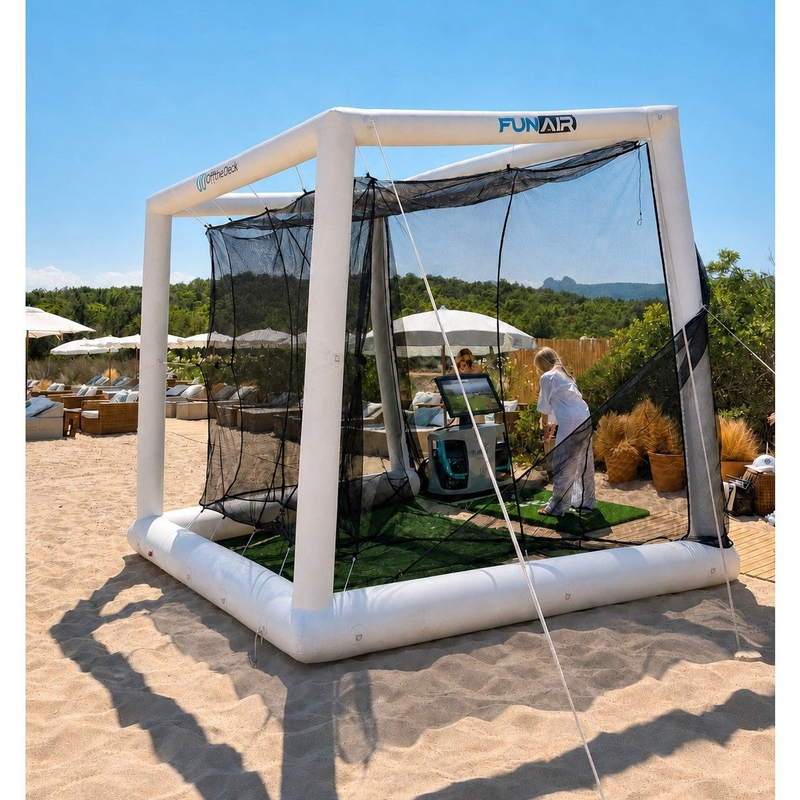 Off the Deck Cube Inflatable Golf Practice Net with a golfer hitting off a turf mat into the net on a beach.