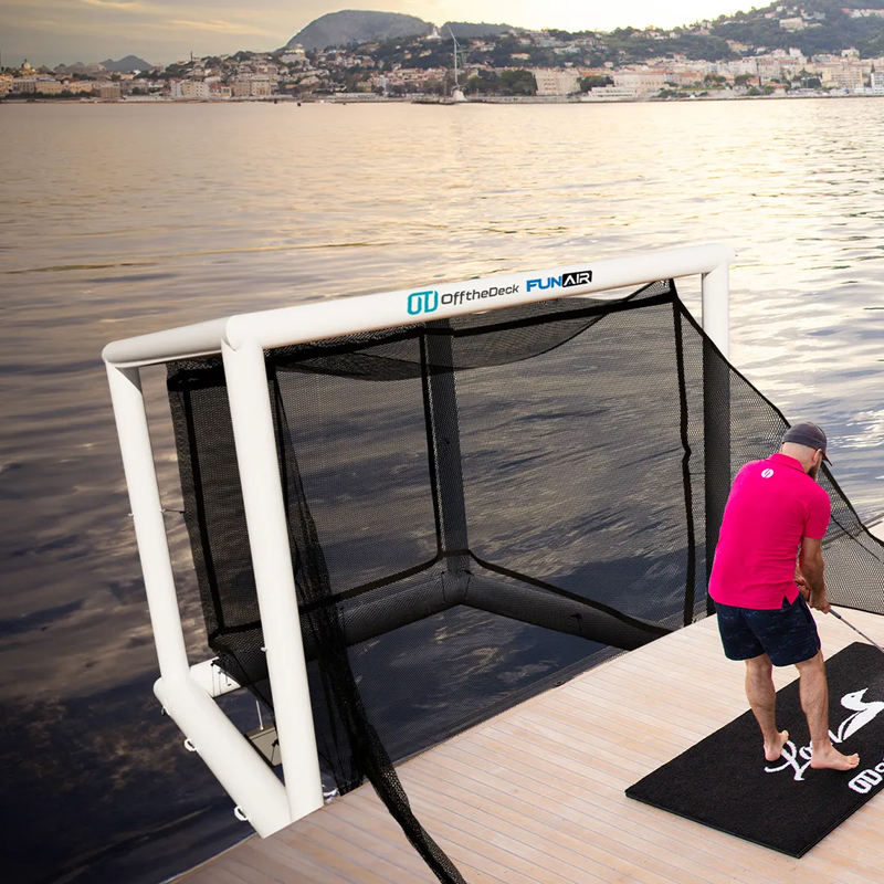Off the Deck Cube Inflatable Golf Practice Net on a yacht platform beside a golf simulator console.