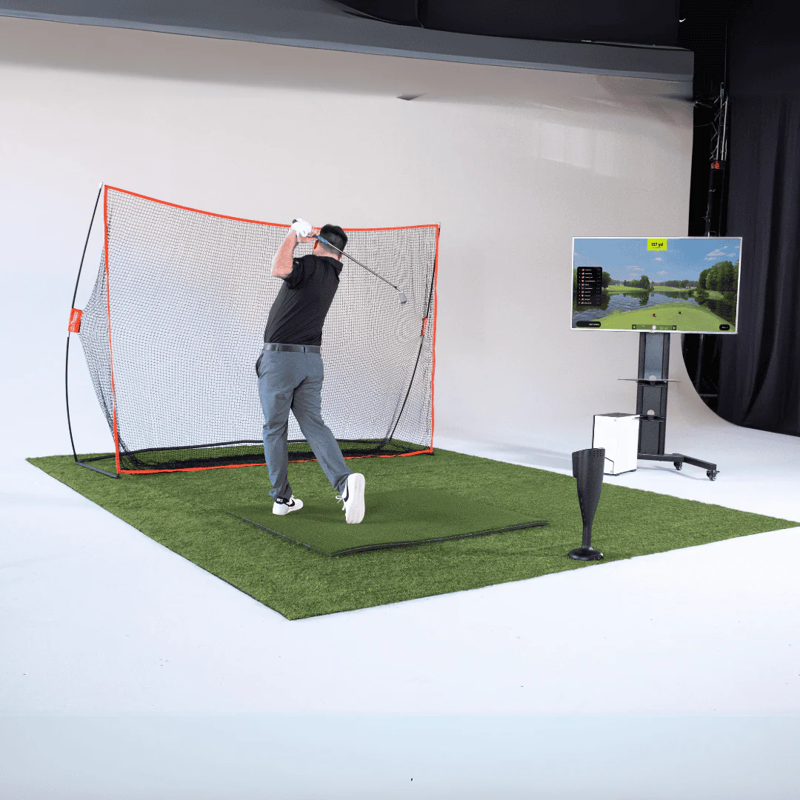 Red Stakes Golf One Golf Starter Bundle golfer swinging in studio with full setup.