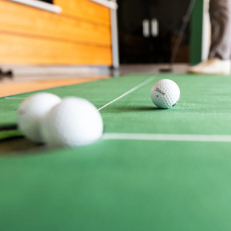 SIG LITE Indoor Putting Green 3&#39; x 8&#39; with close view of golf balls and putting hole.