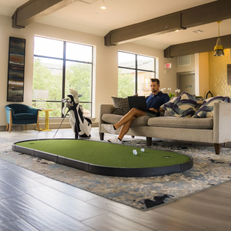 SIGPRO Gimme Putting Green in living room with golfer.