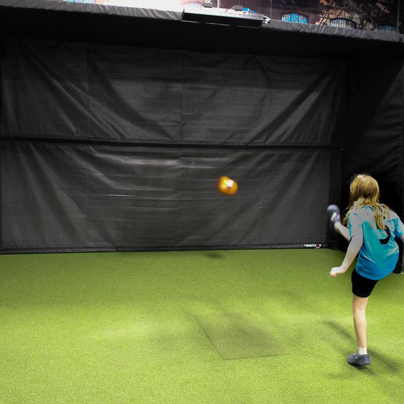 The SportScreen Parlour 16H Golf Simulator Enclosure girl kicking a soccer ball using multisport attachment.