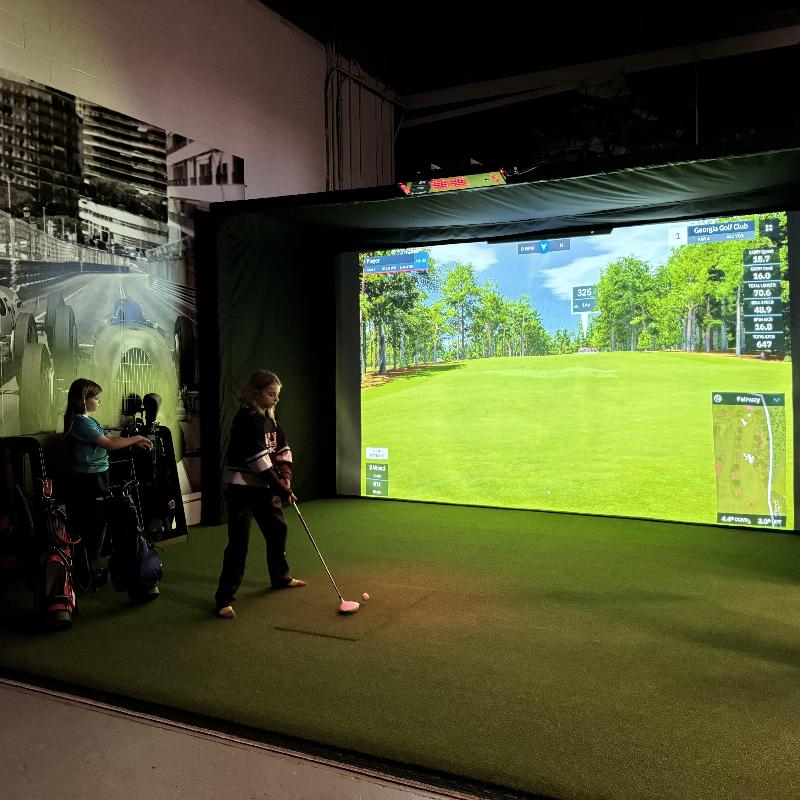 The SportScreen Parlour 16H Golf Simulator Enclosure golf studio with kids playing a round of golf.