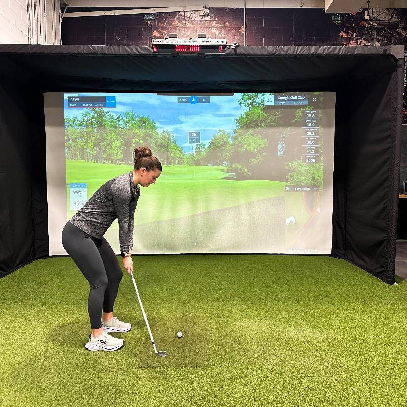 The SportScreen Parlour 16H Golf Simulator Enclosure parlour golf studio girl golfing.