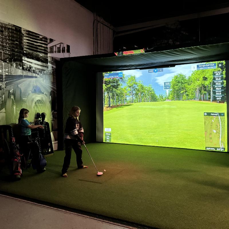 The SportsScreen Parlour Series Golf Simulator Enclosure kids playing a round of golf.