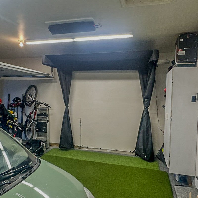 The SportsScreen Vanish LITE Series Golf Simulator Enclosure side screens pinned with car parked.