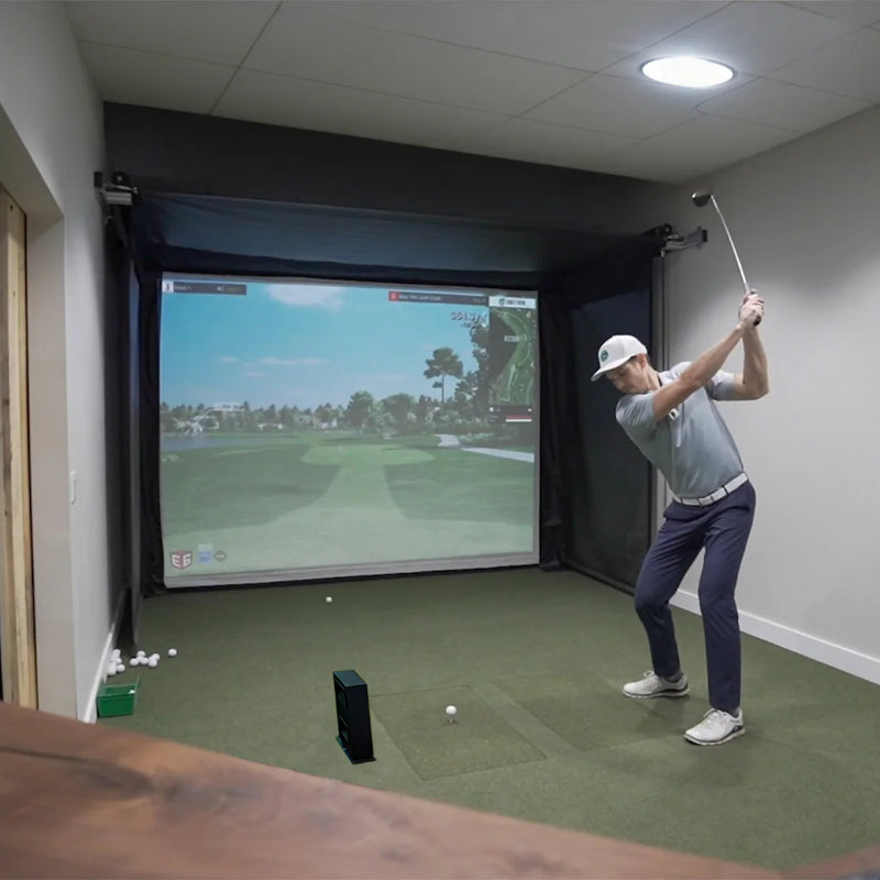 The SportsScreen Vanish Series Golf Simulator Enclosure golfer swinging indoors.
