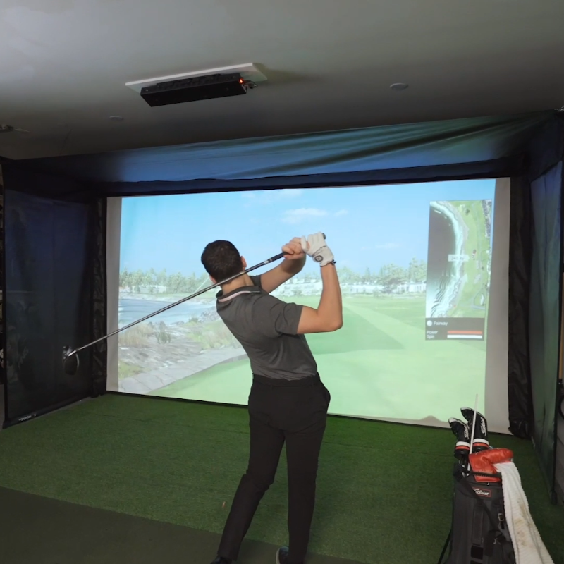 The SportsScreen Vanish Series Golf Simulator Enclosure man swinging on simulator.