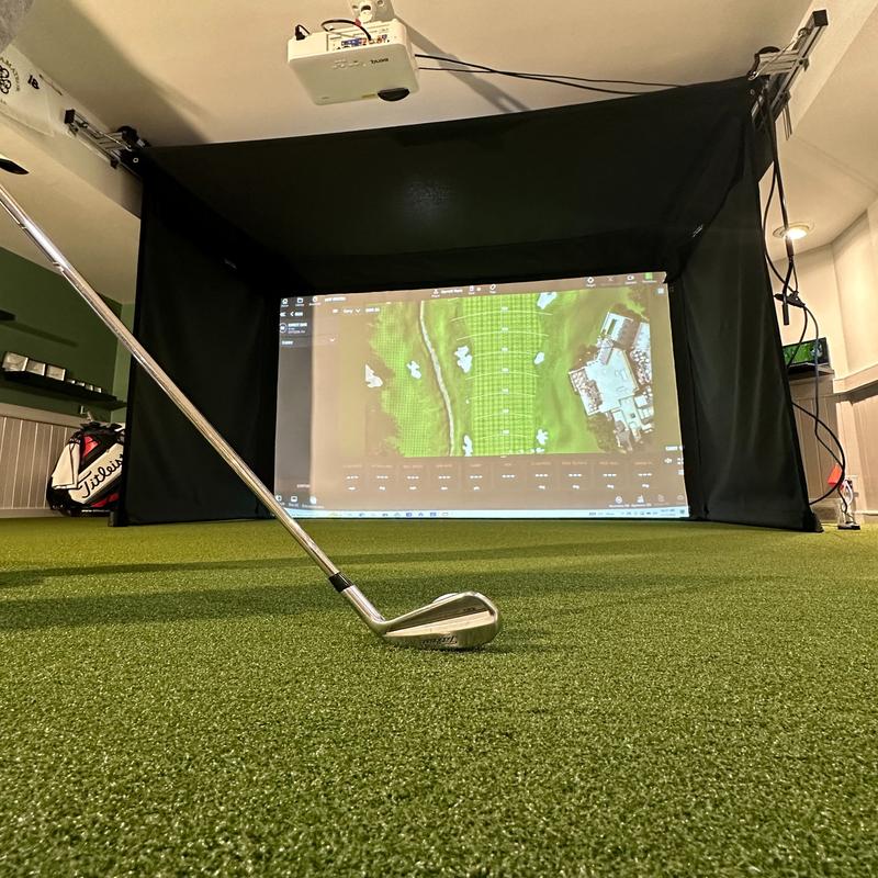 The SportsScreen Vanish Series Golf Simulator Enclosure person teeing up.