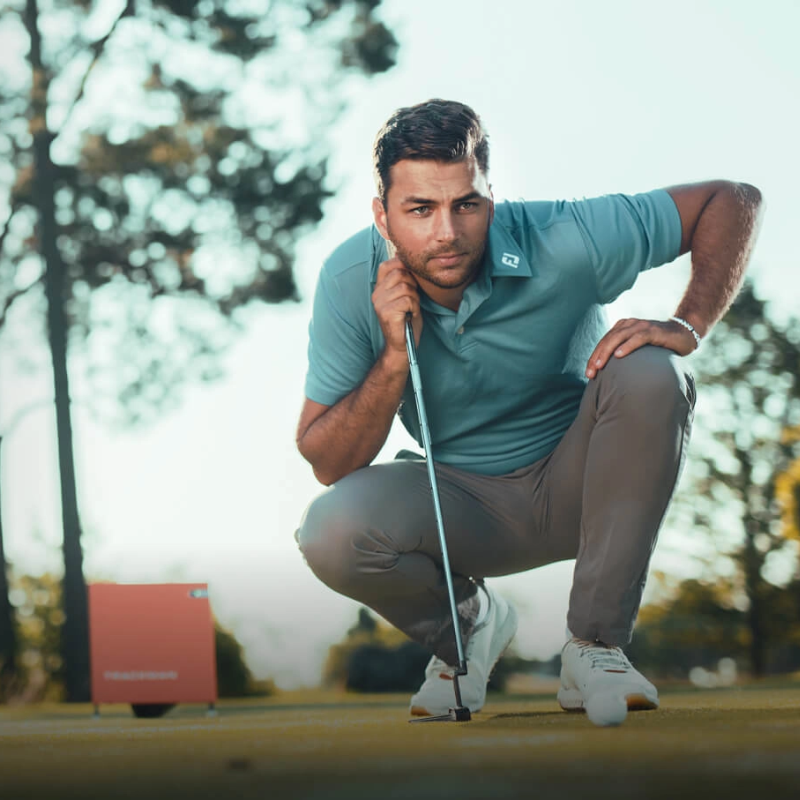 Trackman 4 Golf Launch Monitor golfer reading putt orange device in background.