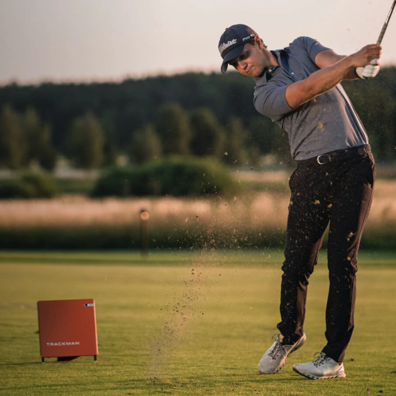 Trackman 4 Golf Launch Monitor golfer swinging club orange launch monitor on fairway.
