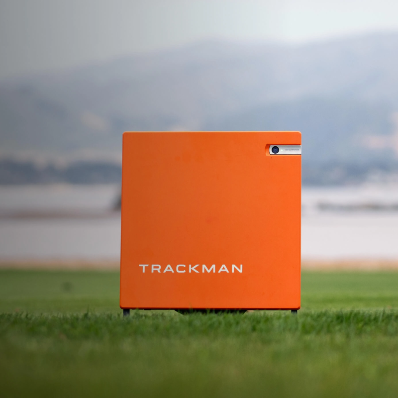 Trackman 4 Golf Launch Monitor outdoor shot on grass orange case.