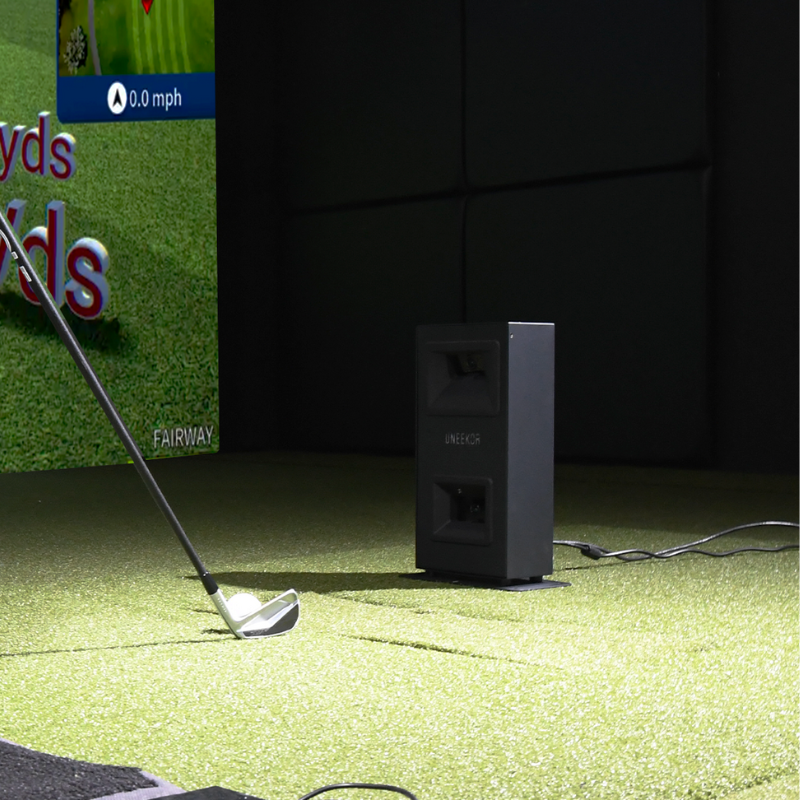 Uneekor EYE MINI LITE Launch Monitor with golf club and ball in a simulator room.