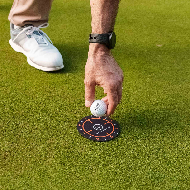 Golfer positioning a ball beside a Ghost Hole target.
