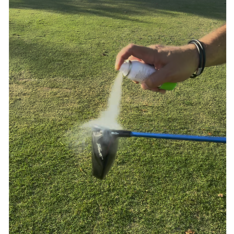 Golfer spraying a light coat of InkPact Micron onto a clubface outdoors.